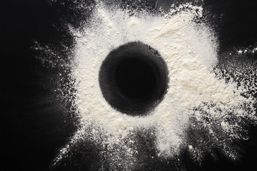 Baking concept on black background, sprinkled flour circle with copy space