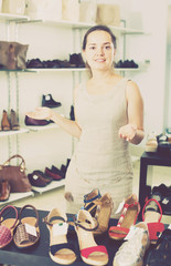 Footwear shop positive girl posing with different shoes