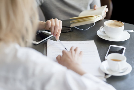 Close-up of two women with notebook, document and cell phones