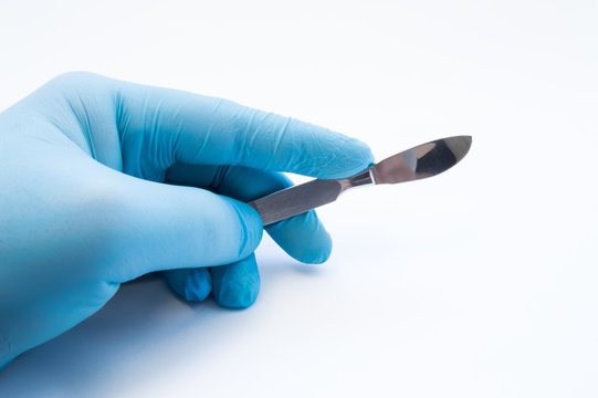 Hand holding scalpel. Palm of surgeon dressed in blue glove holding scalpel. Concept photo for surgeries, procedures, treatment, plastic surgery operation, work of surgical departments and hospitals