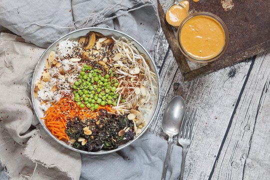 Buddha bowl of kale, carrot, mung bean sprouts, rice, peas, button mushrooms, and roasted almonds