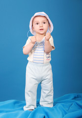 Serious kid stands against a blue background wearing a sailor suit