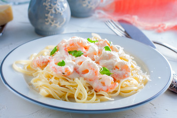 Italian pasta fettuccine in a creamy sauce with shrimp close-up on a plate. horizontal