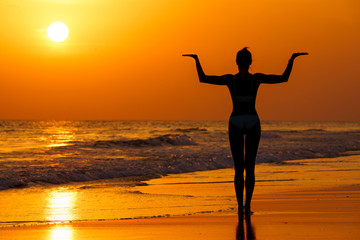 Kobieta ćwicząca jogę na plaży przy zachodzie słońca - obrazy, fototapety, plakaty