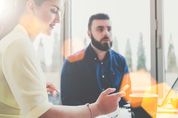 Obraz premium One-on-one meeting. In the foreground sideways to the camera sits a business woman and uses a smartphone.