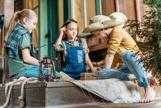 Cute Kids Playing Treasure Hunt With Map On Porch