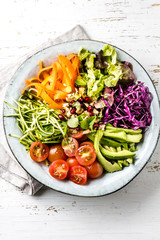 Vegetarian buddha bowl on wooden white background. Raw vegetables and nuts