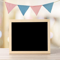 Blank chalkboard standing over colorful party flags and blur background with copy space for text, new year and festival card, banner