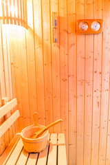 Sauna accessories in sauna room, wooden bucket place on bench and bath thermometer and hourglass on...