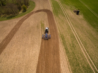 aerial view of a tractor at work - tractor plough cultivating beautiful fields  - agricultural machinery