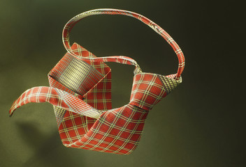 Red with yellow checkered necktie on green fabric background, fashion accessory close up