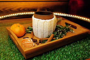 A mug of warm tea with pieces of manadarines on a wooden tray in a cafe