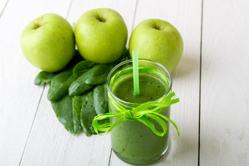 Green smoothie near ingredients for it on white wooden background. Apple, lime, spinach. Detox. Healthy drink.