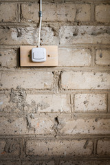 Grunge background. Part of old dirty brick wall and electric switch attached to it.