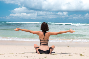 Freedom concept. Freedom and happiness woman on the tropical beach of Bali island, Indonesia. She is enjoying serene ocean nature during travel holidays vacation outdoors.