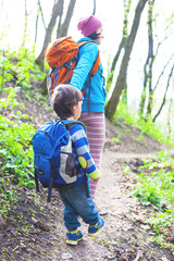 The boy and his mother are walking through the woods.