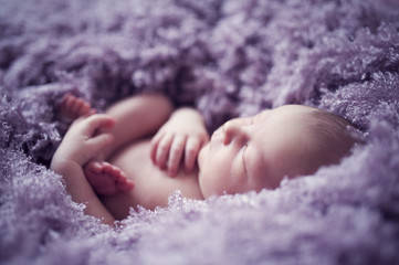 Sleeping baby in violet fur blanket