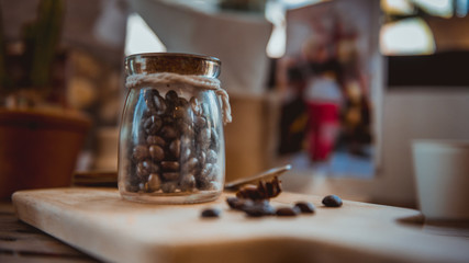 Roasted coffee beans in glass jars closed with a wooden lid.