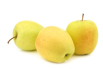 three fresh yellow apples and a cut one on a white background