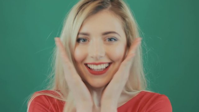 Closeup Portrait of Young Surprised Woman with Red Sensual Lips. Cute Blonde with Long Hair Grimacing on Green Background in Studio.