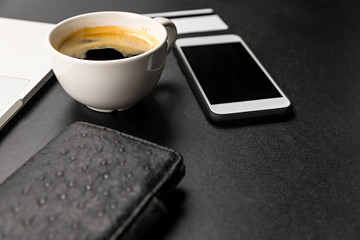 Close-up view of smartphone and cup of fresh hot espresso coffee