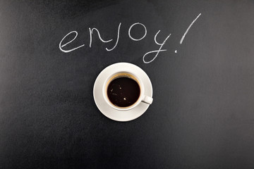 top view of coffee mug steam and Enjoy lettering isolated on black