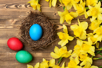 Fototapeta na wymiar traditional easter colorful painted egg in nest, spring yellow narcissus