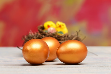 Obraz na płótnie Canvas easter golden eggs and yellow hen, chicken bird in nest