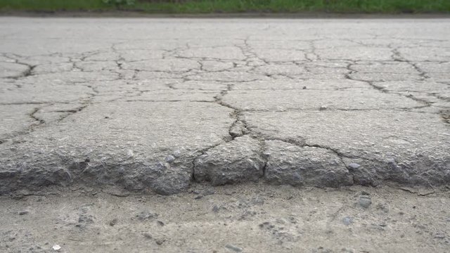 Cracked and broken asphalt road. Bad road conditions. Dolly shot.