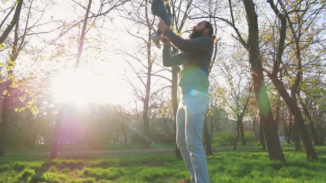 Young father throwing up his little daughter in the air and having fun in park, slow motion