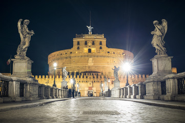 Fototapeta na wymiar Ponte Sant'Angelo bridge crossing the river Tiber and Castel Sant'Angelo (AD 135), mausoleum of Hadrian, now a museum and art gallery illuminated at night in the heart of Rome.