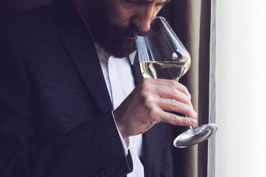 man tasting a glass of white wine