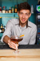 Young Barman offers alcohol cocktail in night club bar