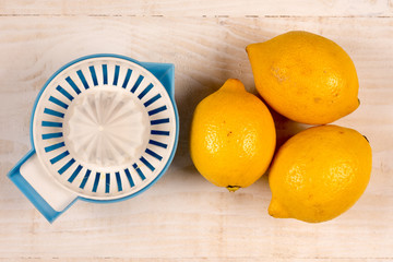 Flat lay above three lemons and plastic strainer