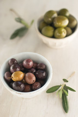 Italian aperitives. Green and black olives (kalakama) and olive branches on a light wooden background