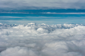 Fototapeta na wymiar Grey cloud cover seen from above aginst blue sky horizon