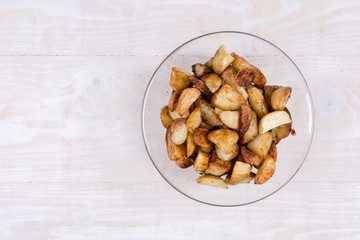 Fried young potatoes in the bowl above wooden background