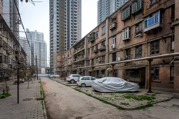 Zelfklevend Fotobehang Une allée entre deux vieux immeubles de la ville de Xi'an et des buildings modernes en fond et des voitures garées © Olivier Tabary