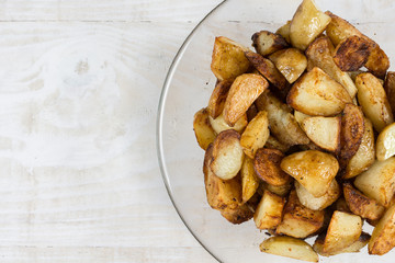 Fried young potatoes in the bowl above wooden background