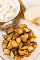 Fried young potatoes with cow cheese on the plate