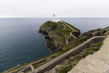 Grand view of South Stack Lighthouse perched atop South Stack Rock from the switchback staircase of...