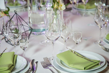 Closeup of table elegant served with green fabric napkins, small willow twigs and bouquet of flowers. Everything is ready for holiday celebration. Horizontal color photography.