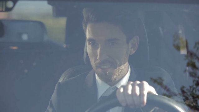 Giovane uomo elegante sale in automobile e si allenta la cravatta