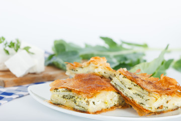 Homemade cheese and spinach pie on a white plate. Shallow depth of field.