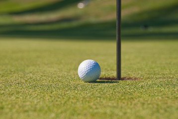 Golf ball on green with flag.