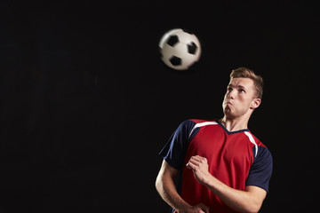 Professional Soccer Player Heading Ball In Studio © Monkey Business