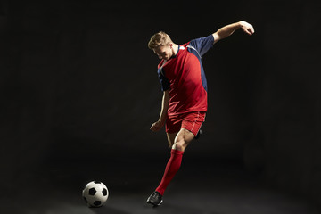Professional Soccer Player Shooting At Goal In Studio