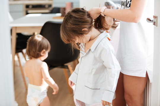 Mother Doing Hair To Her Little Daughter At Home