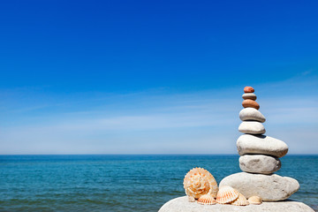 Fototapeta na wymiar concept of peace and harmony. A pyramid of white stones and shells on background of summer sea