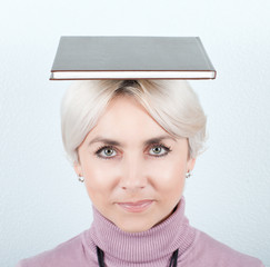 Portrait of smiling woman with book on her head